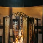 Grilled fish cooked on an open flame, showcasing traditional culinary methods with a rustic touch.