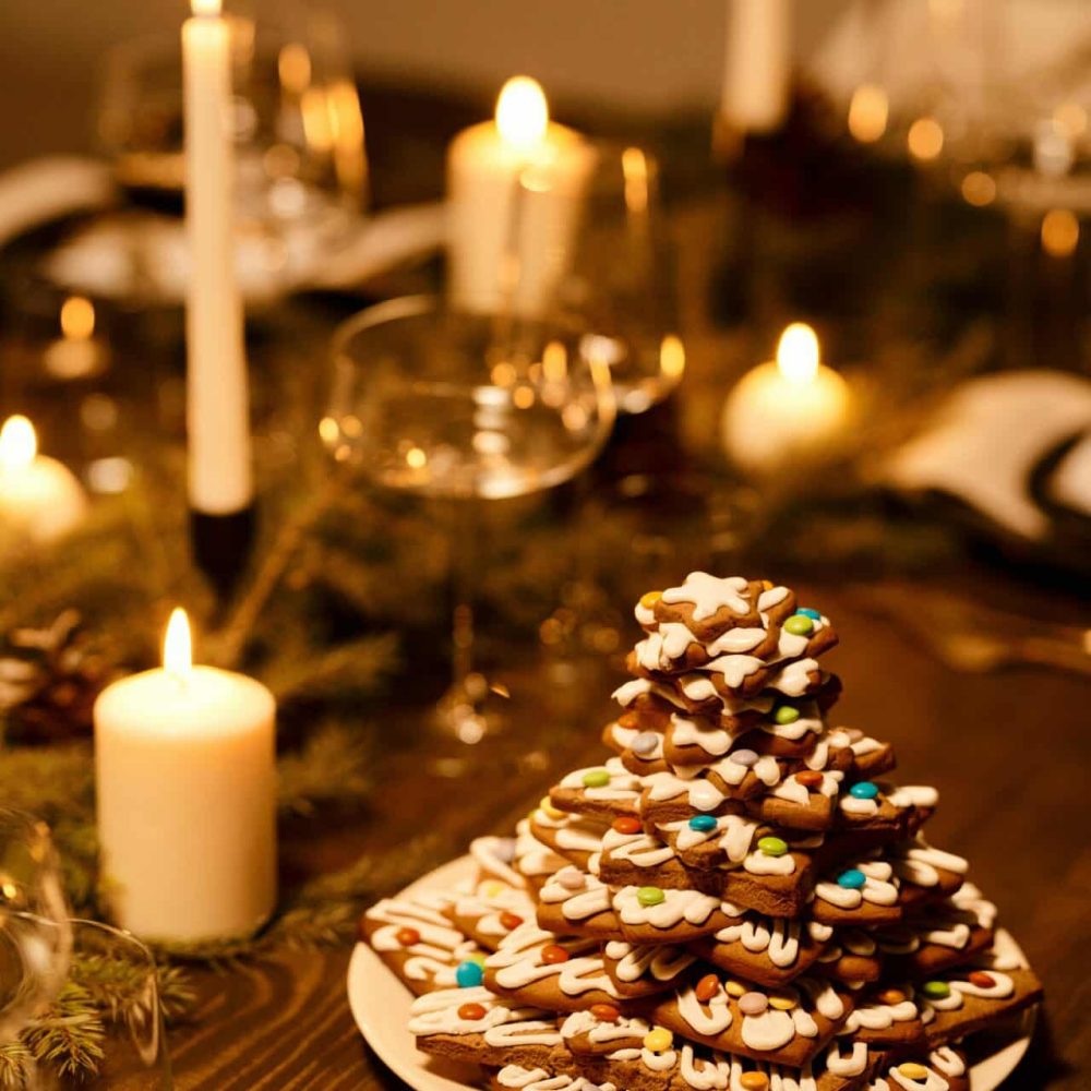 A cozy Christmas dinner setup with decorated cookies and candlelight ambiance.
